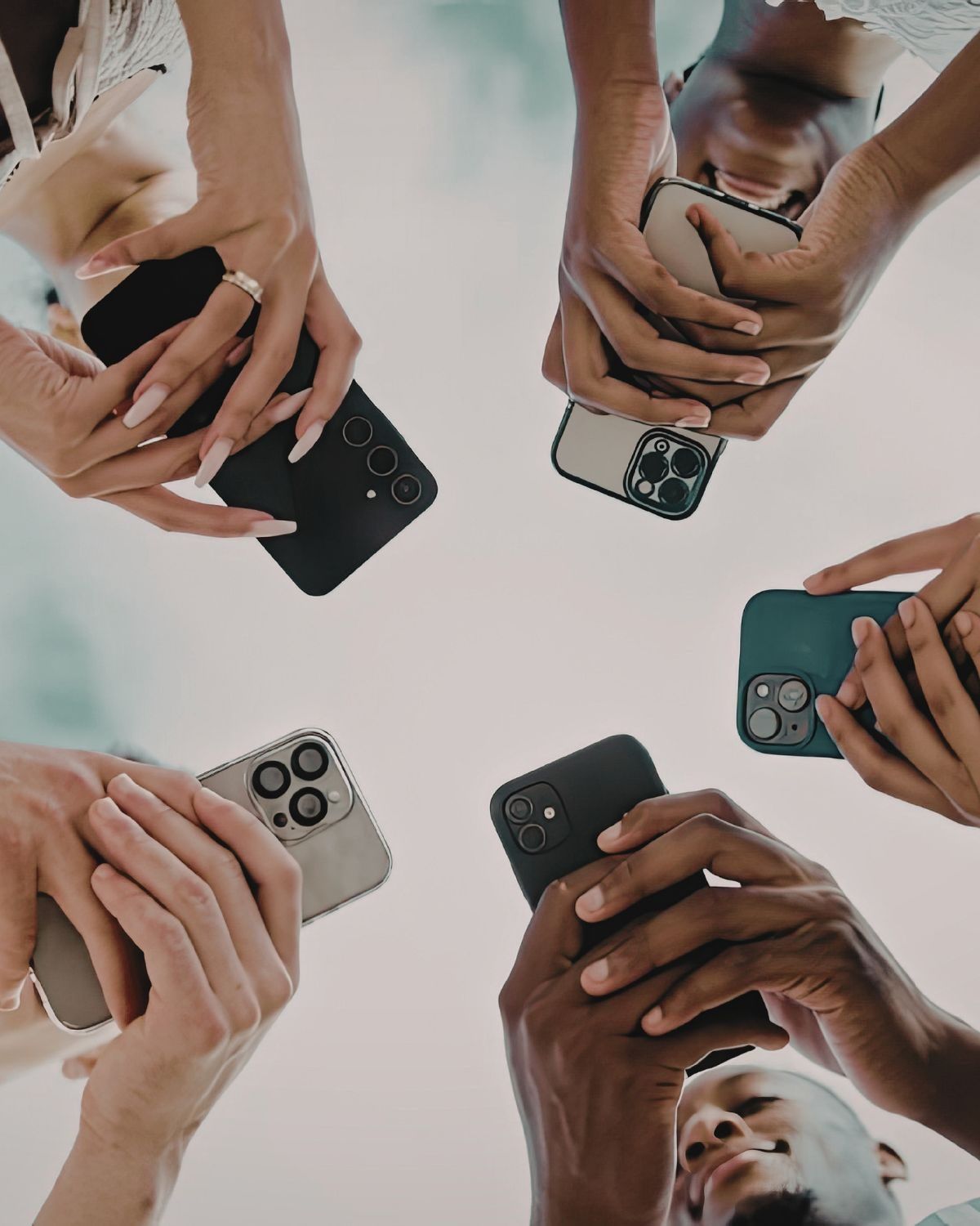 Un círculo de manos diversas sosteniendo teléfonos, los rostros ocultos: la ironía de estar juntos y solos a la vez.